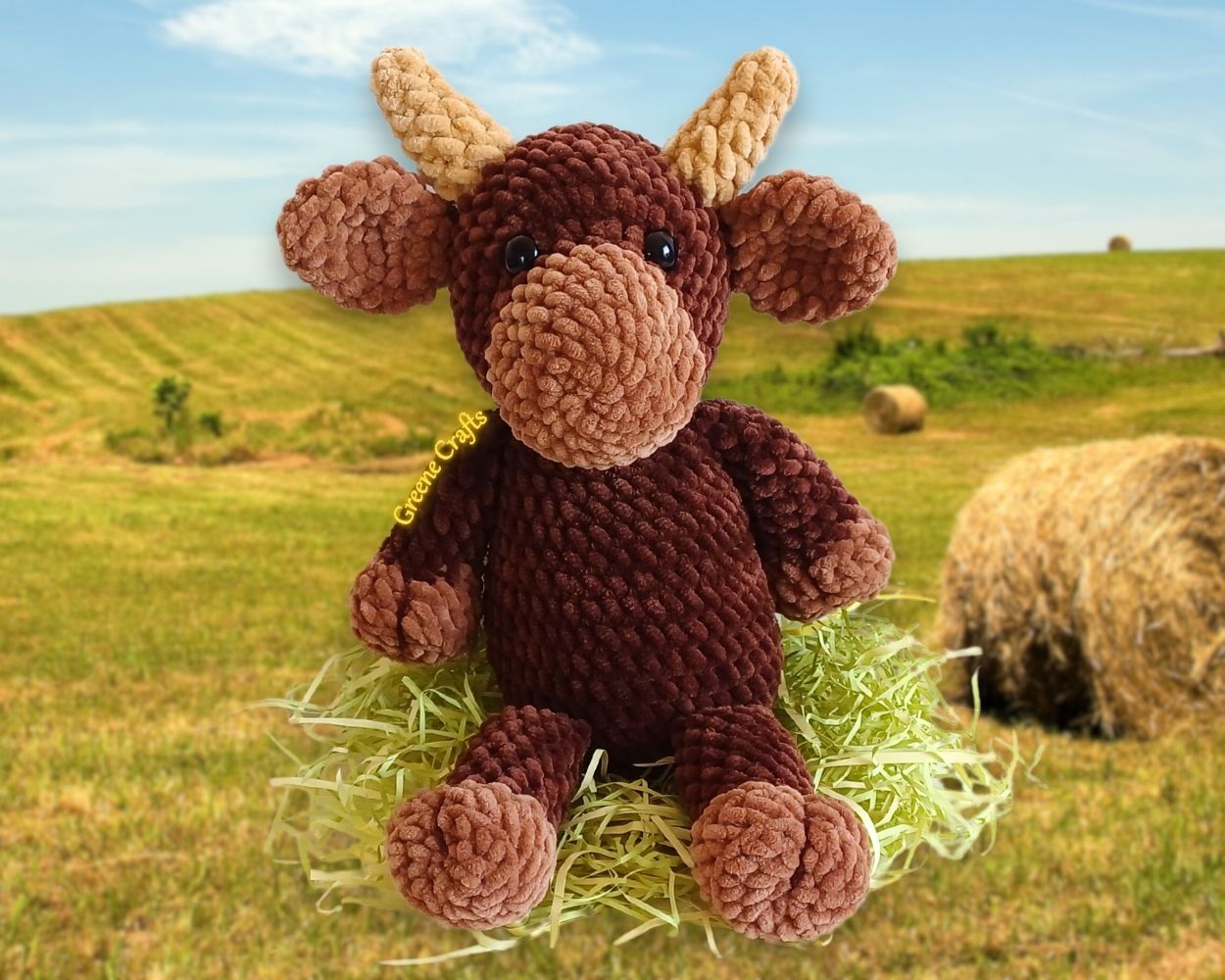 Bandit the Bull crochet plush sitting on a grassy meadow, made from the low-sew amigurumi crochet pattern.